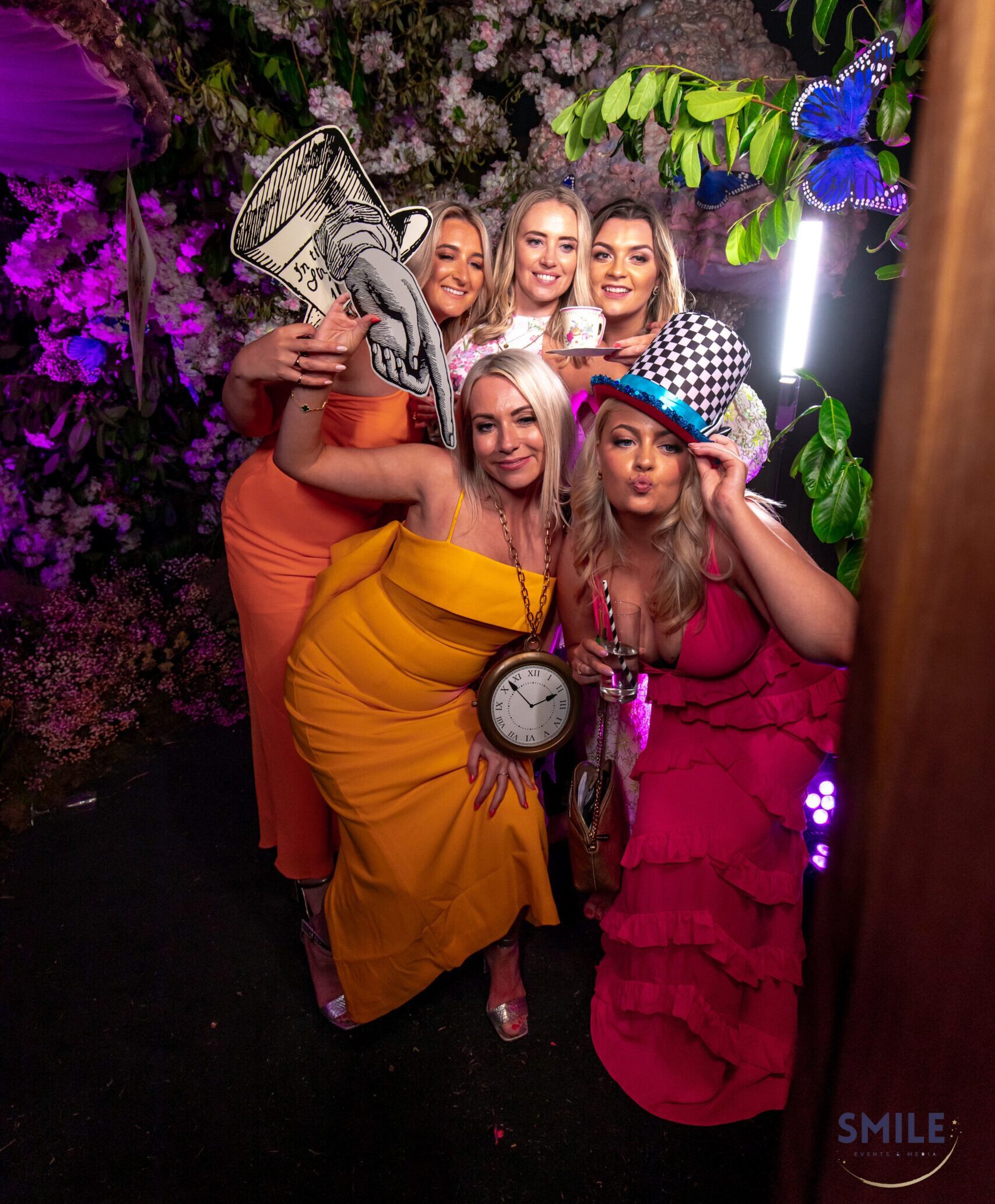 Sleek open-air boutique photo booth setup for London event with bespoke floral backdrop and Alice in Wonderland theme
